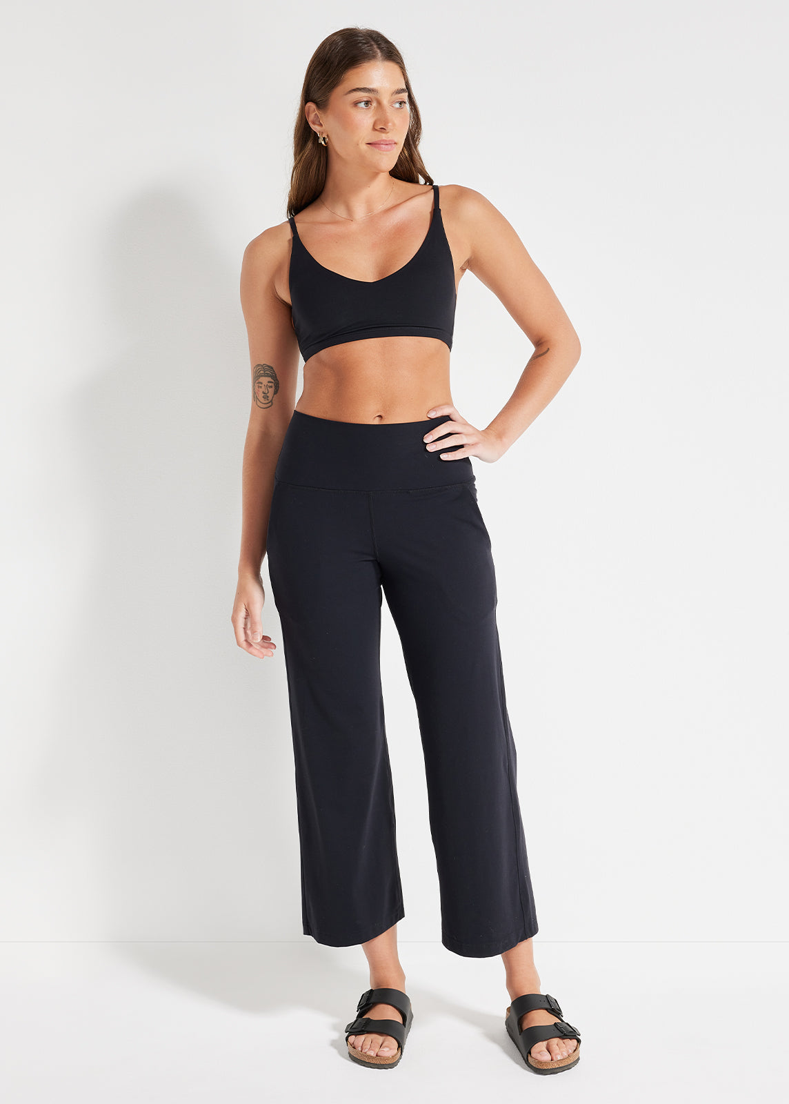 Model wearing relaxed fit crop pants and cropped top indoors