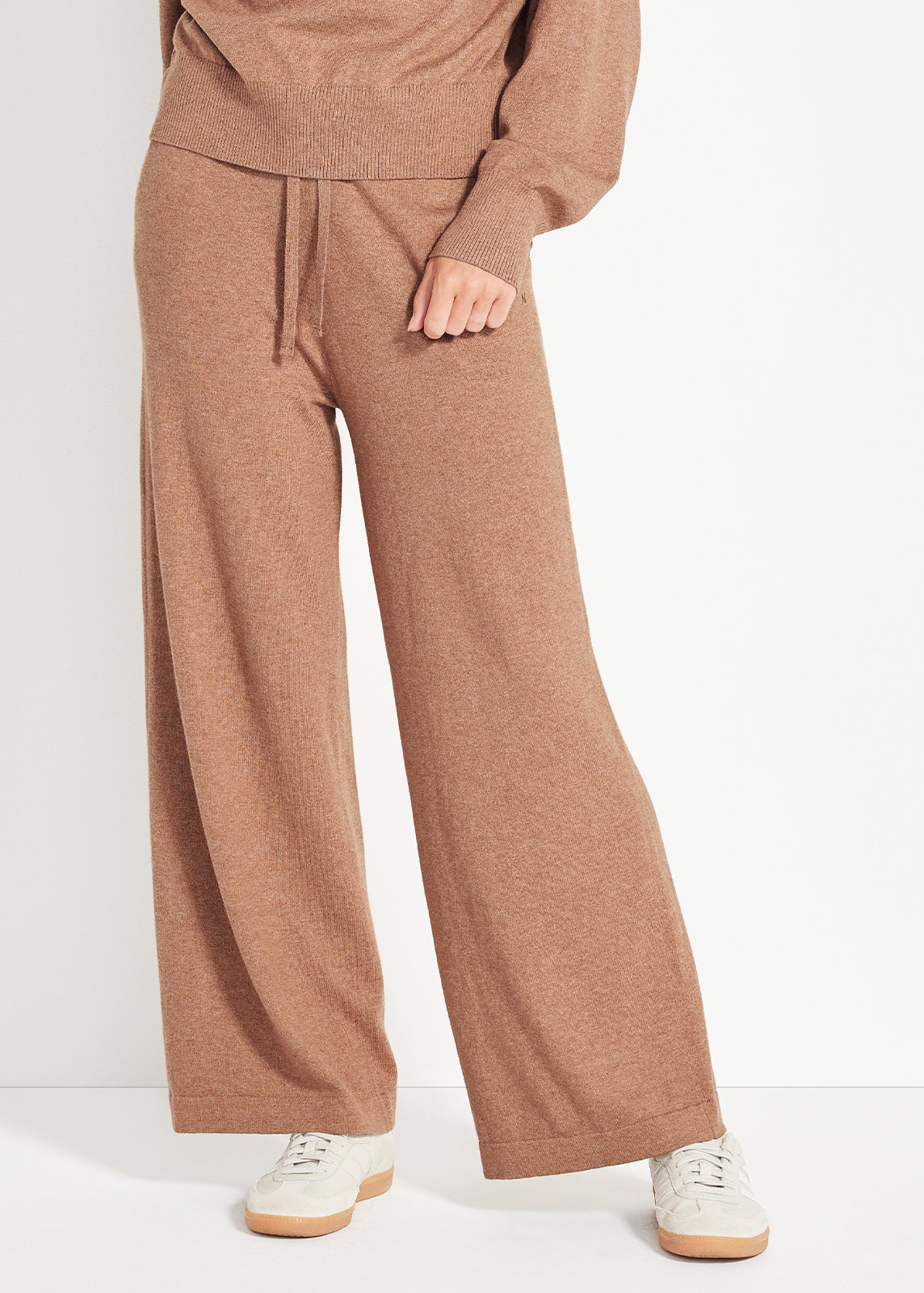 Model wearing camel wide-leg knit pants with ribbed waistband and white sneakers