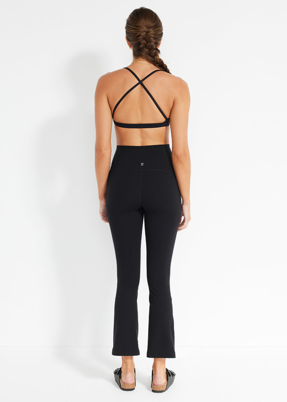 Back view of black flared pant and cross-back bra with minimalist, sleek design