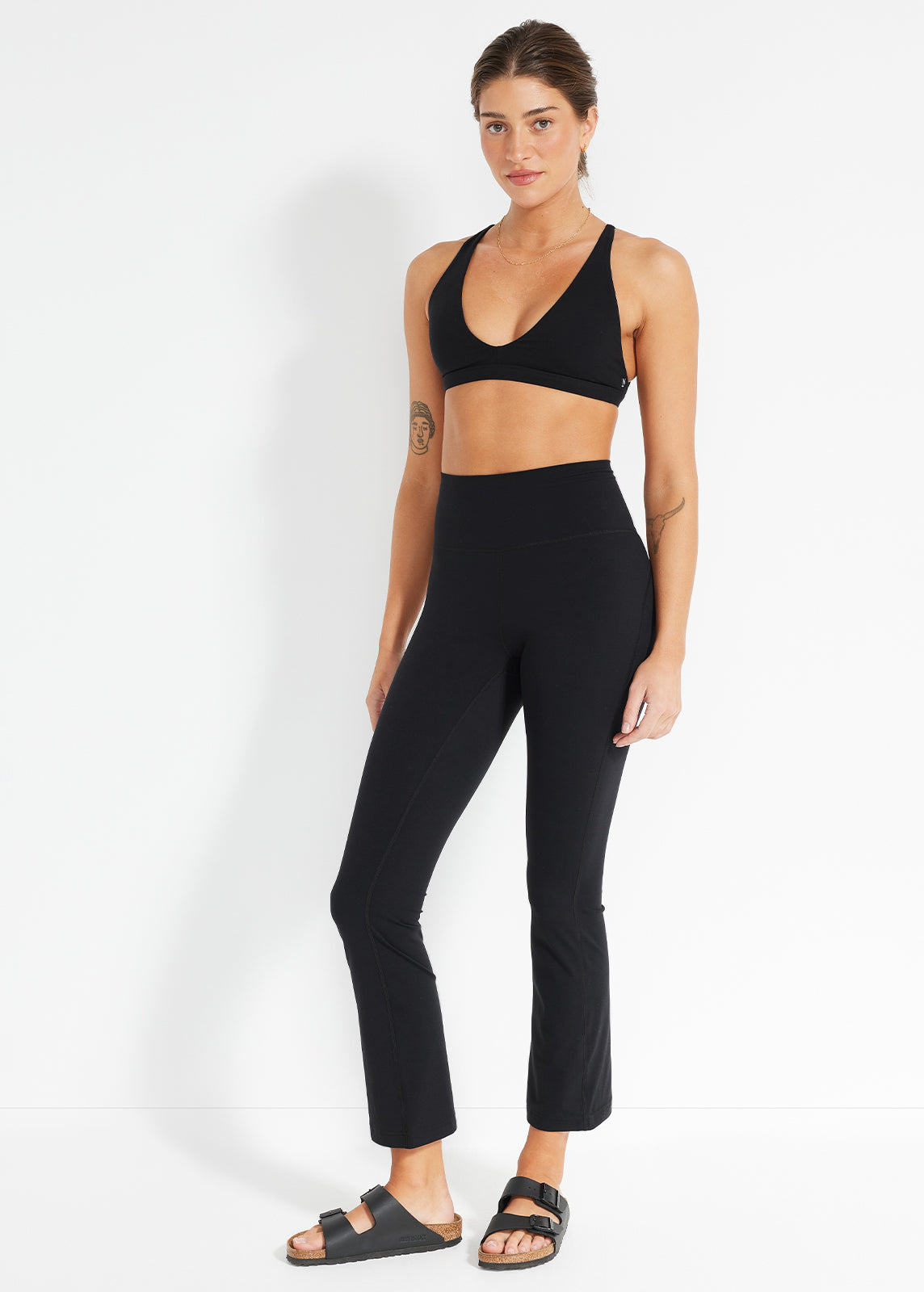 Model wearing black flared leggings and scoop-neck sports bra in studio