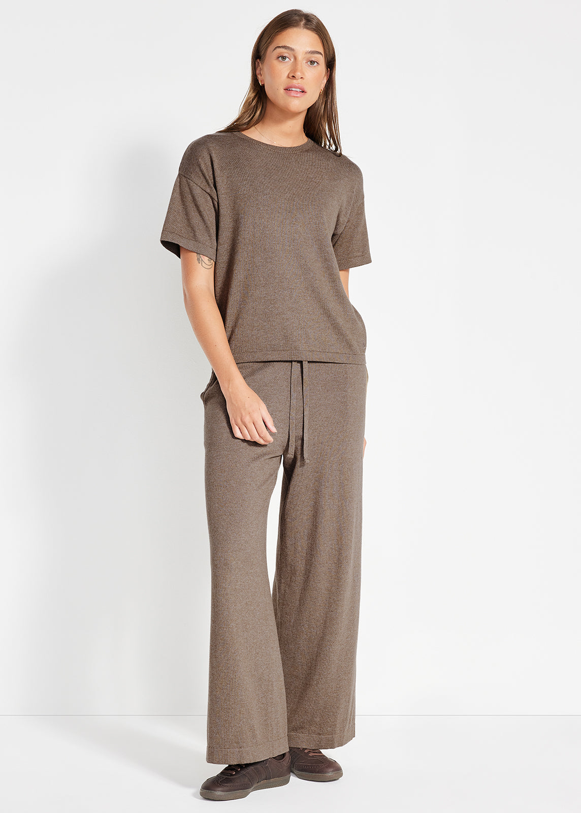 Model wearing brown knit lounge set with zip-up jacket and relaxed pants