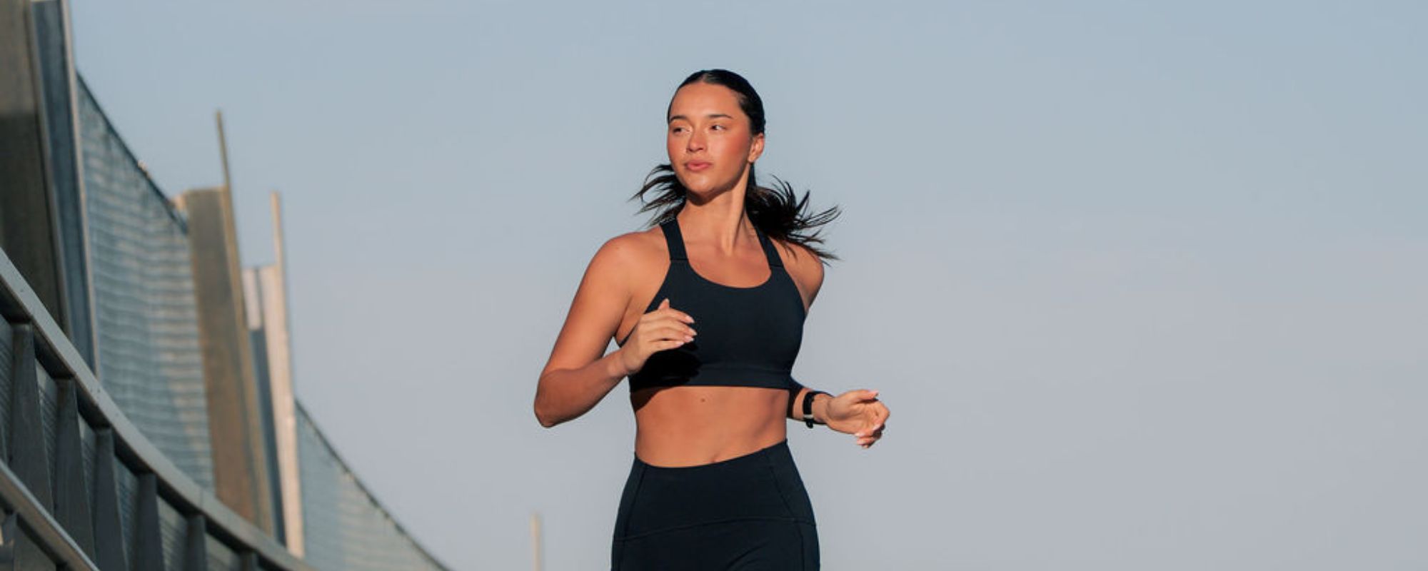 Runner jogging on a bridge wearing Nimble In Pace activewear.