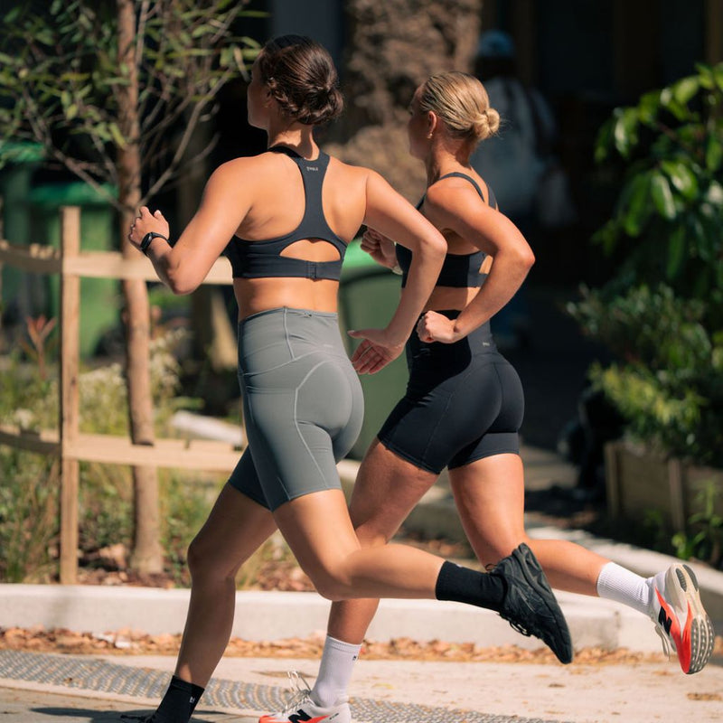 Two women sprinting outdoors in Nimble In Pace running sets.