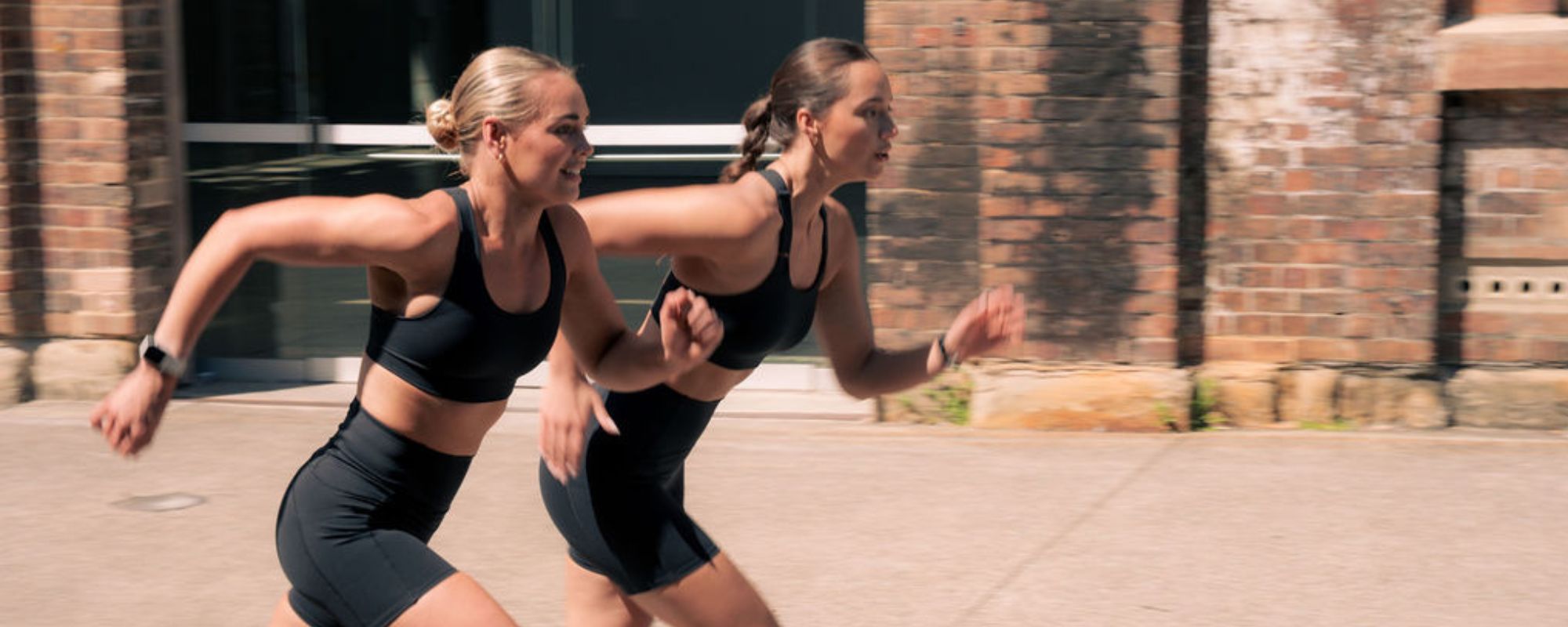 Two women running outdoors in black Nimble In Pace activewear.
